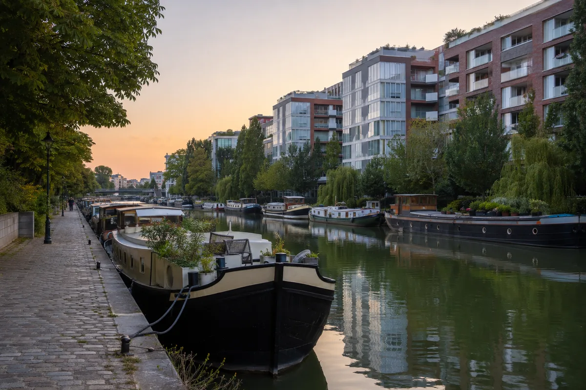Quai de canal parisien bordé de péniches et d’immeubles contemporains